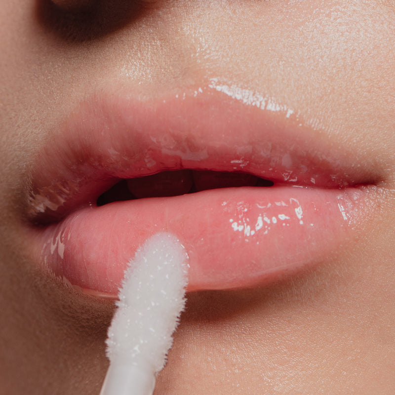 Close-up of a person applying LONDONTOWN's Volumizing Peptide Lip Serum to their lips with a soft applicator for fuller lips.