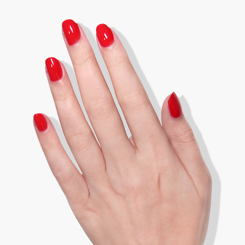 A hand with fingernails painted in LONDONTOWN's Londoner Love red crème polish is shown against a white background.