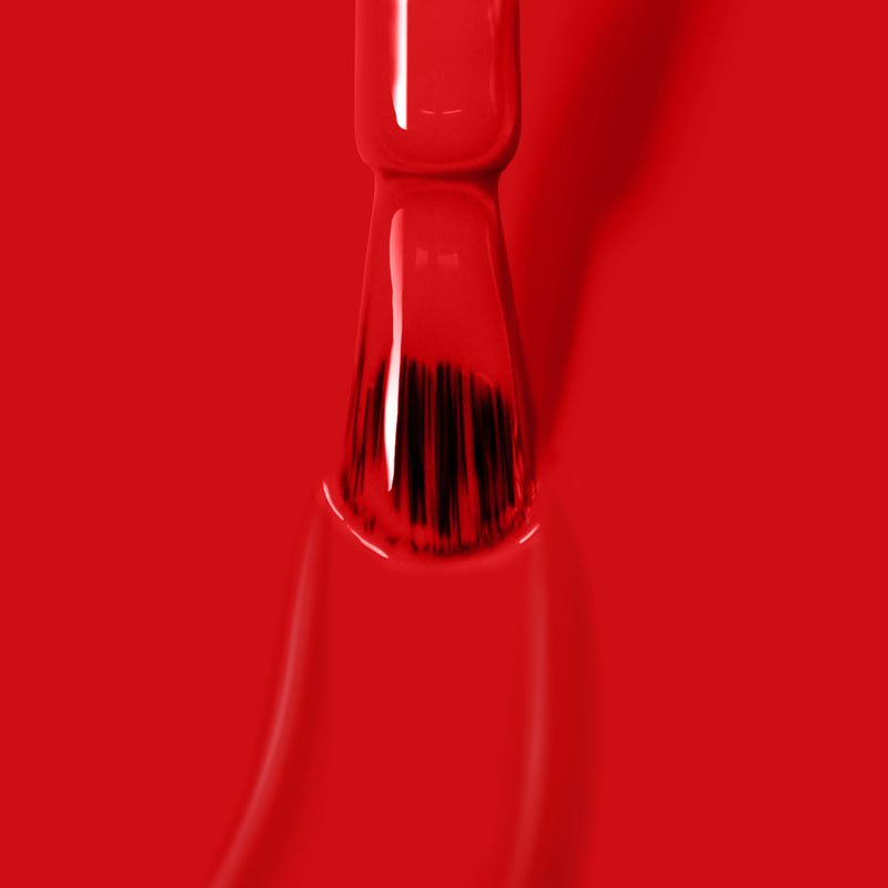 Close-up of a brush painted with LONDONTOWN's Londoner Love glossy red crème polish on a red background.