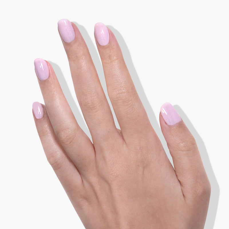 A hand with neatly manicured nails painted in LONDONTOWN's Love Bug light pink crème shade on a white background.