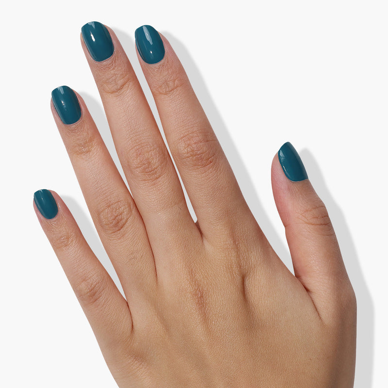 A hand adorned with LONDONTOWN's Magpie peacock teal-colored painted nails on a white background makes a sophisticated statement.
