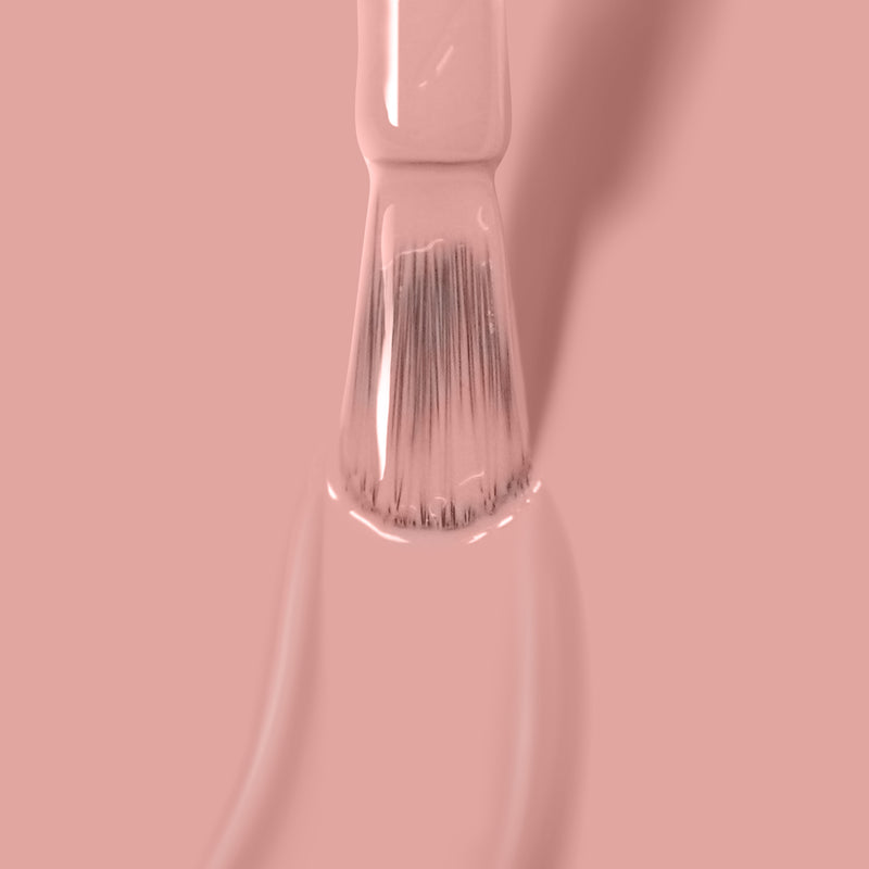 Close-up of a brush applying LONDONTOWN's Make Me Blush light pink gel color nail polish on a smooth surface, showcasing its super pigmented formula.