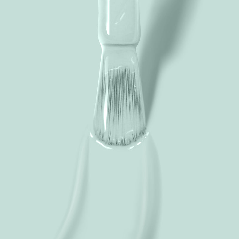 Close-up of a paintbrush with LONDONTOWN's Mint No Chip paint on its bristles, reminiscent of mint creme, against a light green background.