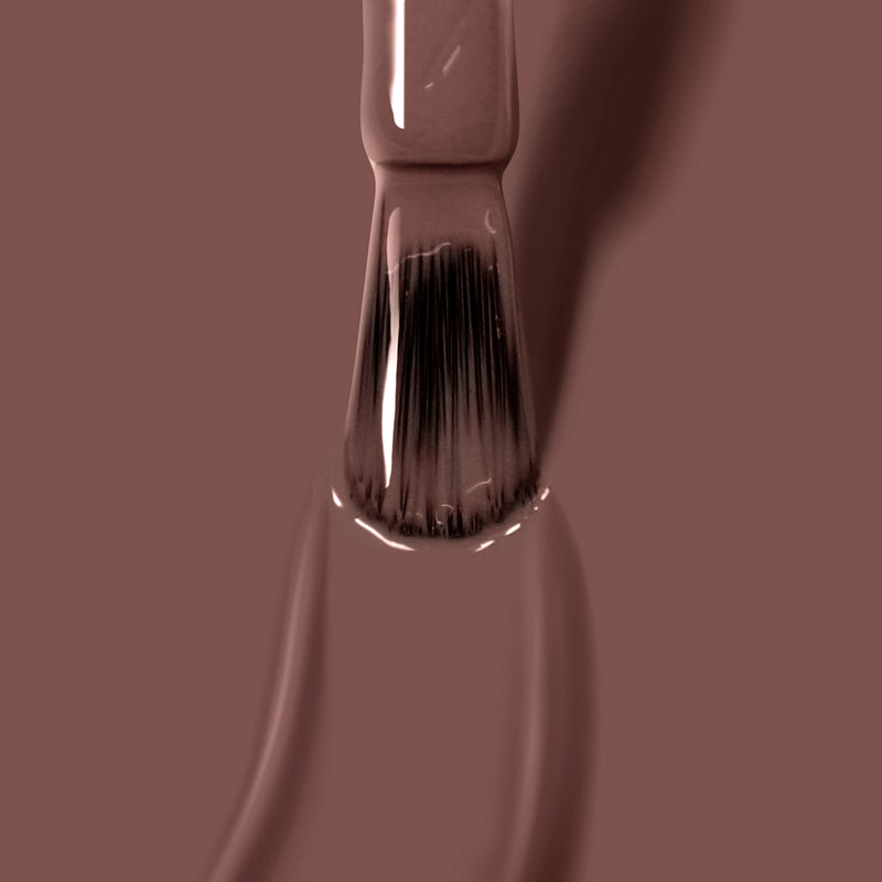 A close-up of a paintbrush applying smooth, Florium Complex infused Mudslide by LONDONTOWN deep brown nail polish on a flat surface.