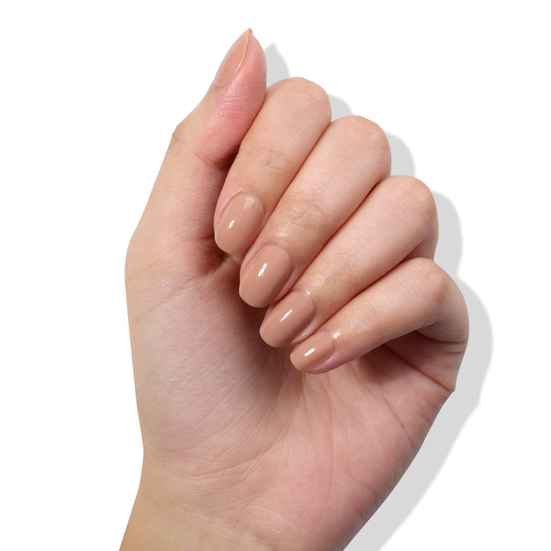 A hand with neatly manicured, almond-shaped nails painted in LONDONTOWN's Perfecting Nail Veil #6, a glossy nude with a hint of color, exudes elegance and care against a white background.