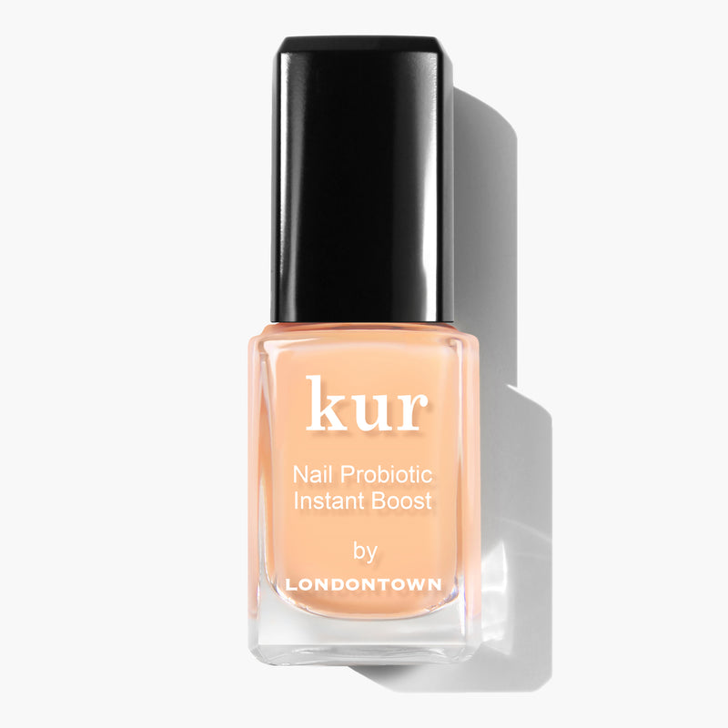 A bottle of LONDONTOWN Nail Probiotic Instant Boost, featuring a black cap and light peach-colored liquid inside, designed as a transformative nail mask perfect for strengthening thin or weak nails.