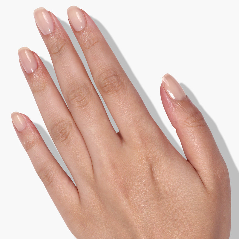A hand with neatly manicured nails painted in LONDONTOWN's Perfecting Nail Veil #1 exudes subtle power-packed elegance against a plain white background.