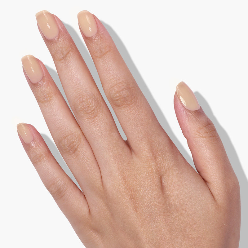 A hand with neatly manicured nails painted in LONDONTOWN's Perfecting Nail Veil #2, offering a hint of color and subtle elegance, is shown against a white background.