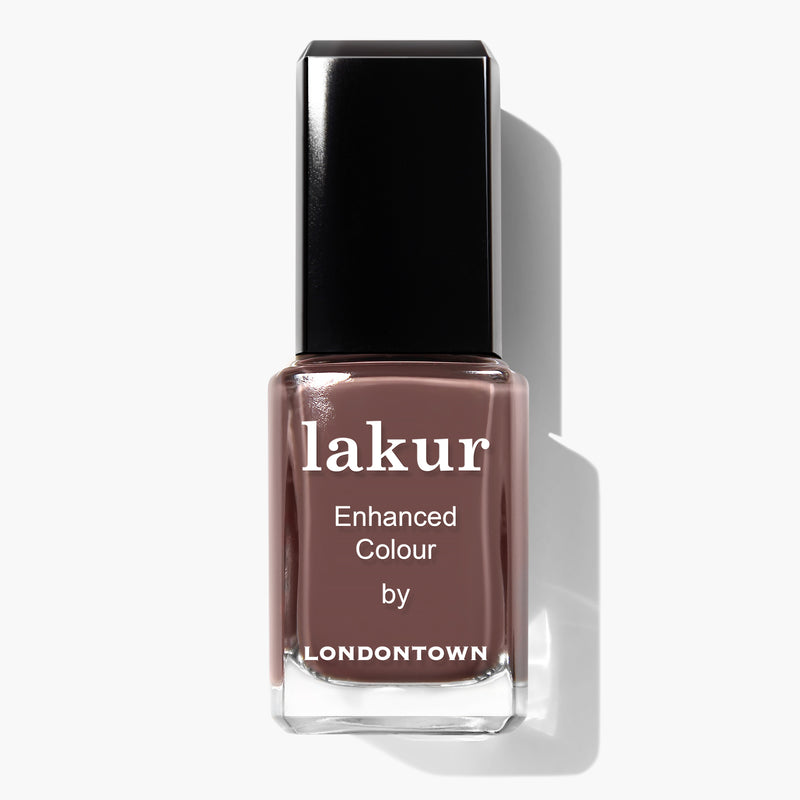 A bottle of LONDONTOWN Lakur Enhanced Colour nail polish in the shade Natural Charm, featuring a creamy mauve purple hue and a black cap. This vegan, cruelty-free formula ensures your nails look stunning while staying kind to the planet.
