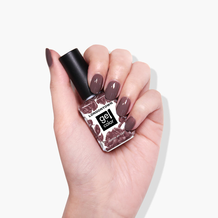 A hand with manicured nails holding a bottle of LONDONTOWN&