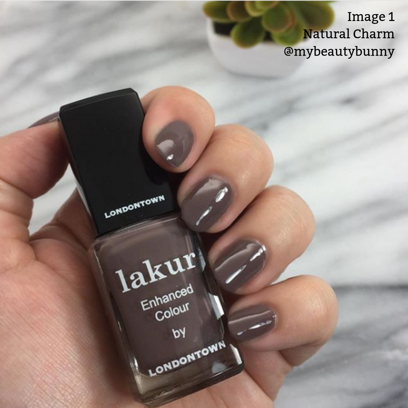 Close-up of a hand holding a bottle of LONDONTOWN "Natural Charm" nail polish in creamy mauve purple, with matching manicured nails. A small plant is in the background. Text reads: "Image 1 Natural Charm @mybeautybunny".