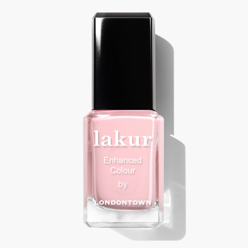 Image of a bottle of LONDONTOWN "Out of Office" lakur nail polish in pastel pink color, labeled "Enhanced Colour." Infused with Florium Complex, the vegan cruelty-free polish features a black cap and casts a slight shadow to the right.