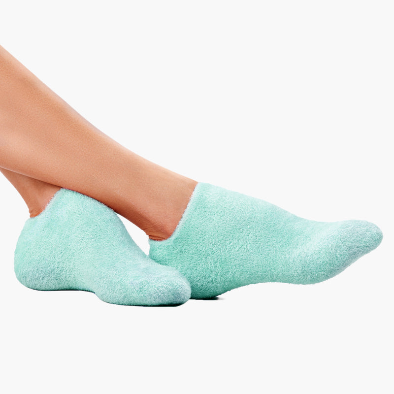 Two feet in Pedi Perfect Moisturizing Spa Socks by LONDONTOWN rest against a white background, promising cozy feet and dreamy sleep.