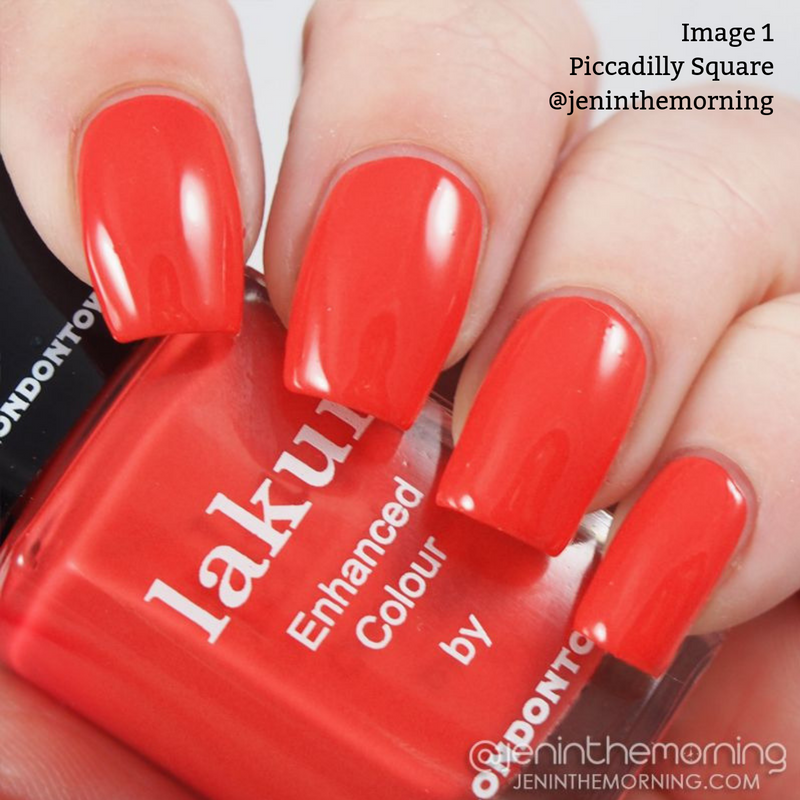 Close-up of a hand with red-painted nails holding a bottle of vegan, cruelty-free LONDONTOWN Lakur nail polish. Text on image reads, "Piccadilly Square @jeninthemorning." The striking Blood Orange Crème shade from the Piccadilly Square collection stands out beautifully.