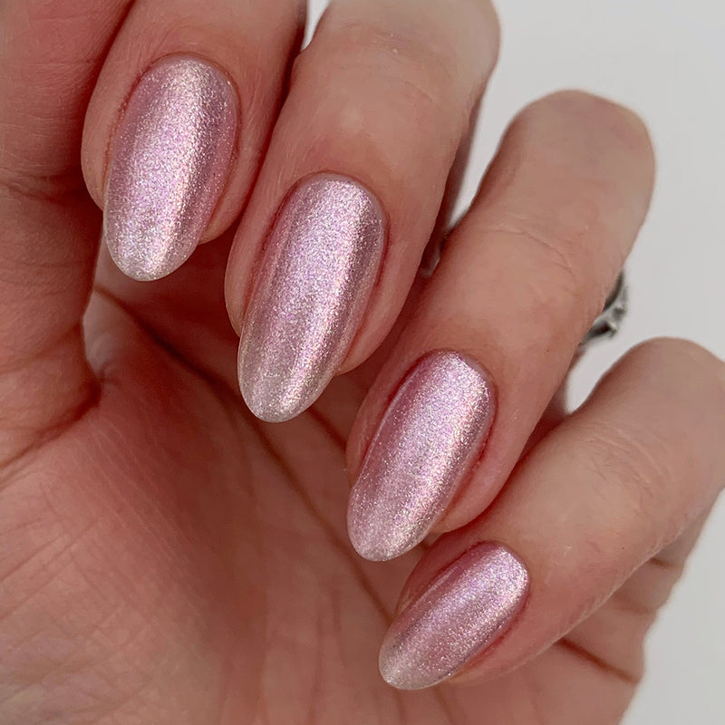 A hand with neatly manicured nails painted with LONDONTOWN's Pink Strawberry polish is shown against a neutral background.