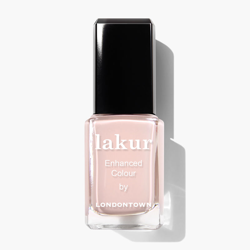A bottle of LONDONTOWN Plié Enhanced Colour Nail Polish in a light, neutral shade reminiscent of Ballet Slipper with a black cap against a white background. This vegan, cruelty-free polish offers an elegant touch without compromising ethics.