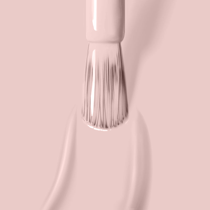 A brush applying LONDONTOWN's Plié nail polish against a matching pink background.