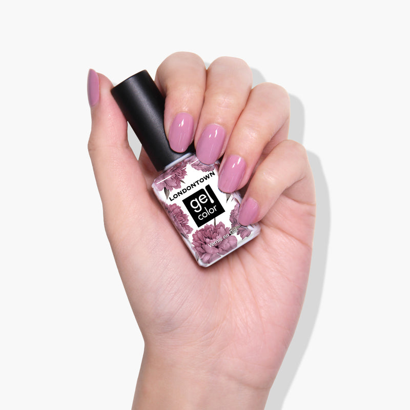 A hand holding a bottle of LONDONTOWN Plush crème gel color nail polish with a floral design, nails painted in a matching shade.