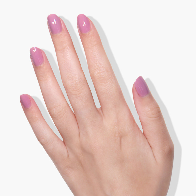 A hand with a light skin tone, seen from the back, displays manicured nails painted in LONDONTOWN's mauve crème gel color called "Plush" against a white background.