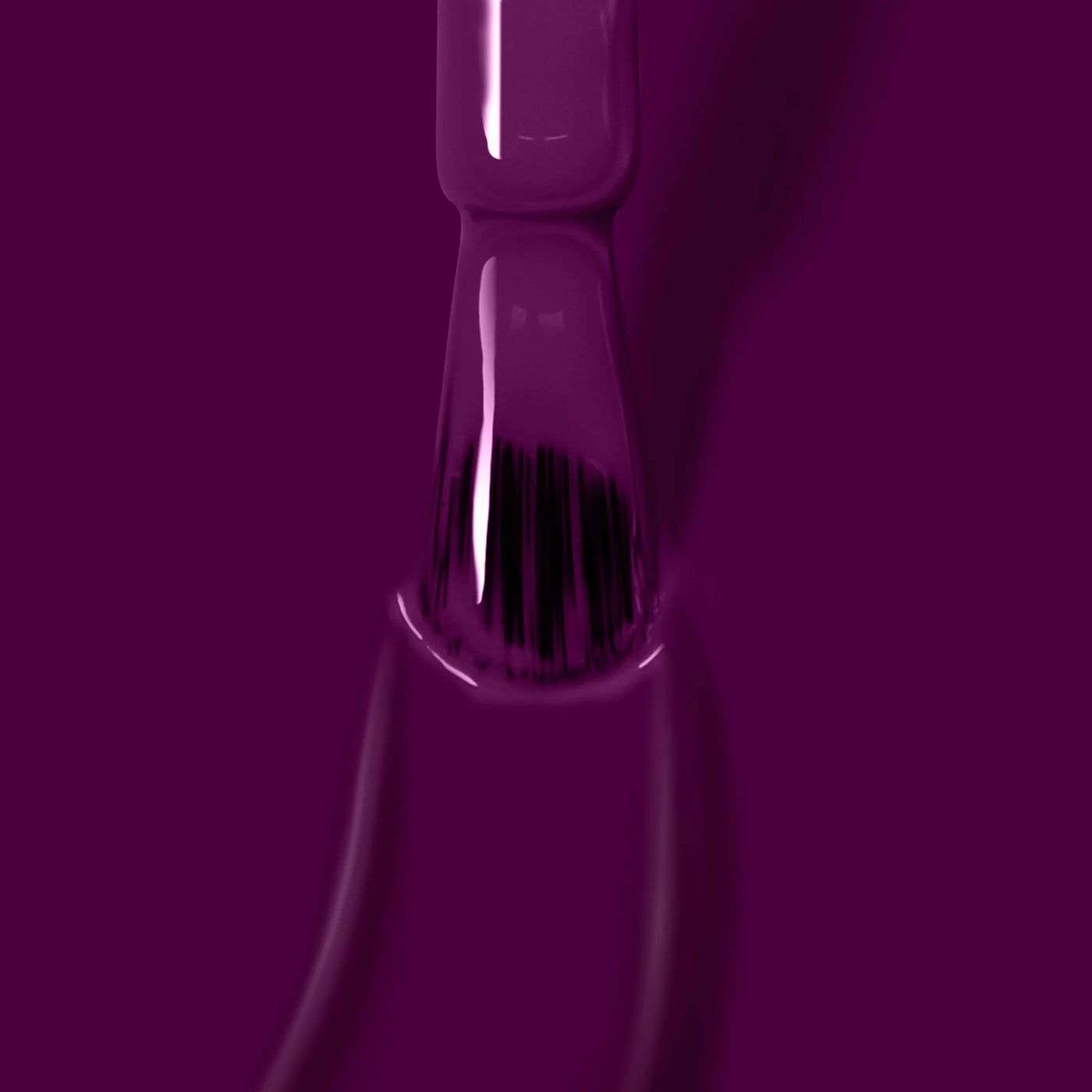 Close-up of a nail polish brush dipped in Portobello Plum (Professional), a deep warm crème by LONDONTOWN, with the rich, vegan cruelty-free nail polish pooling around the tip.