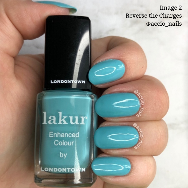 A hand shows off nails painted in a vibrant teal blue color, holding a bottle of LONDONTOWN's Lakur vegan nail polish in the shade "Reverse the Charges." The bottle label reads "Enhanced Colour by Londontown.
