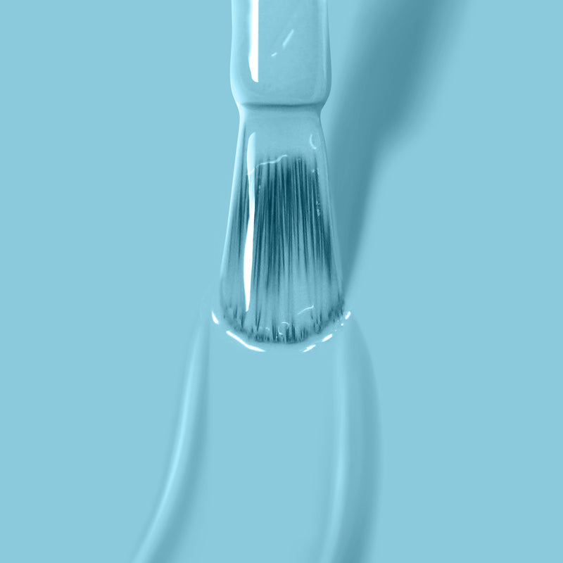 Close-up of a paintbrush with blue paint against a blue background, showcasing fine bristles and glossy wet paint that shimmers like the vibrant "Reverse the Charges" vegan nail polish by LONDONTOWN.