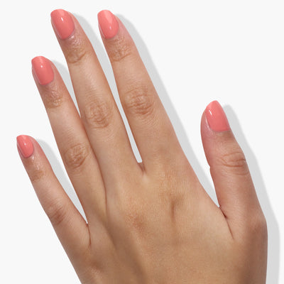 A hand with neatly painted coral-colored fingernails, using the "Rose-Tinted Glasses (Professional)" polish by LONDONTOWN, shown against a plain white background.
