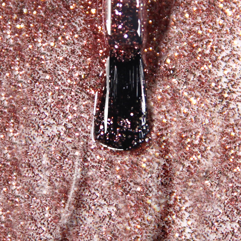 Close-up of a LONDONTOWN polishes brush applying Rosé All Day, a vegan and cruelty-free glittery rose gold polish, onto a surface.