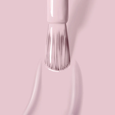 Close-up of a brush applying LONDONTOWN's Rosewater (Professional) light pink, vegan nail polish, leaving smooth, shiny strokes on a pink surface.