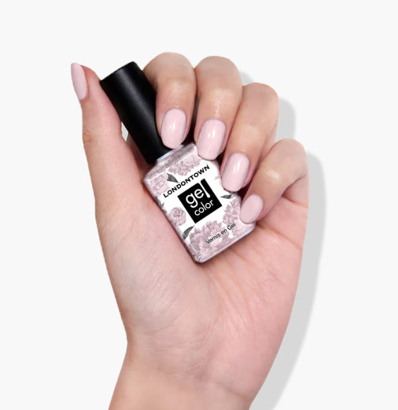 A hand with polished light pink nails holds a bottle of LONDONTOWN Rosewater UV/LED Gel Color nail polish, boasting a high-shine formula and set against a white background.