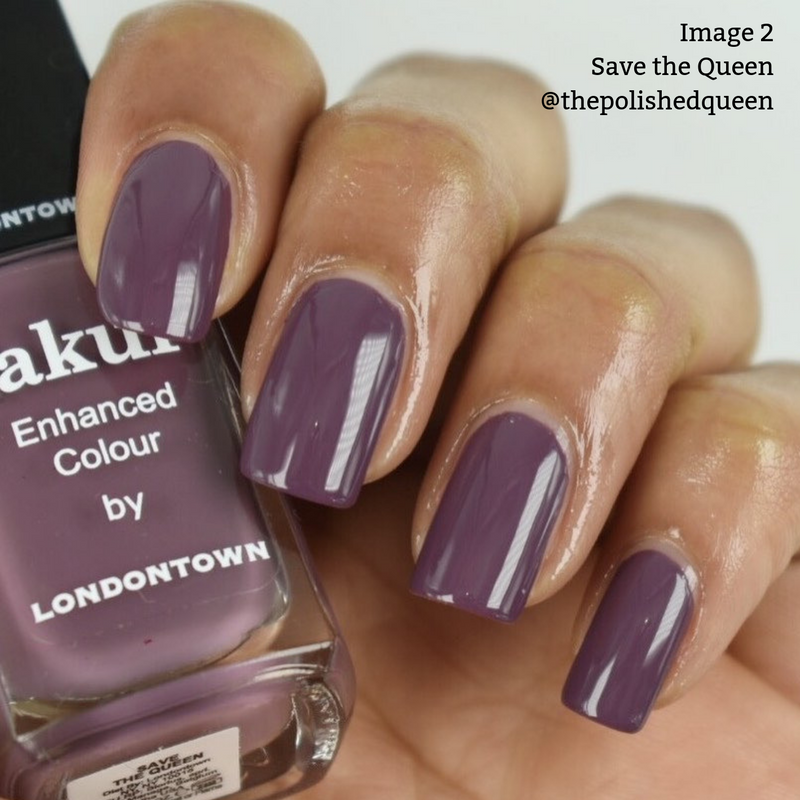 Close-up of a hand with polished nails holding a bottle of LONDONTOWN's vegan, cruelty-free nail polish in the glossy, deep purple shade "Save the Queen.