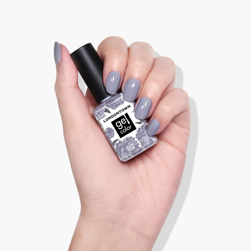 Hand holding a bottle of LONDONTOWN Silver Birch gel color nail polish with nails painted in a matching shade, against a white background.