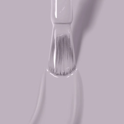 A close-up of a brush applying Silver Birch (Professional), a light gray, formaldehyde-free paint by LONDONTOWN, on a smooth surface.