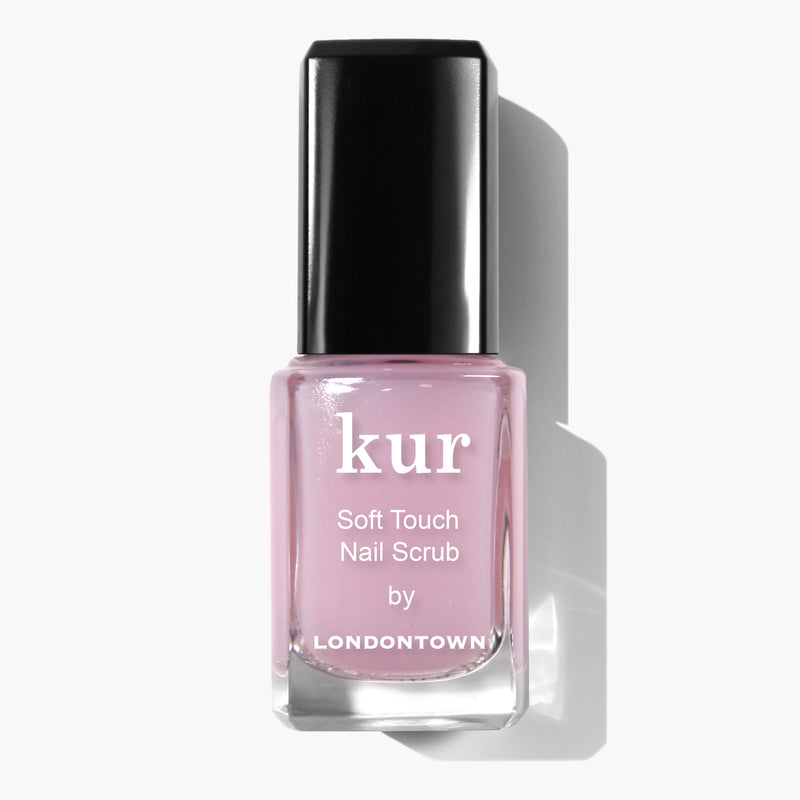 A bottle of LONDONTOWN Soft Touch Nail Scrub, featuring a pink liquid and a black cap against a white background. This vegan, cruelty-free formula is perfect for tackling dry cuticles.