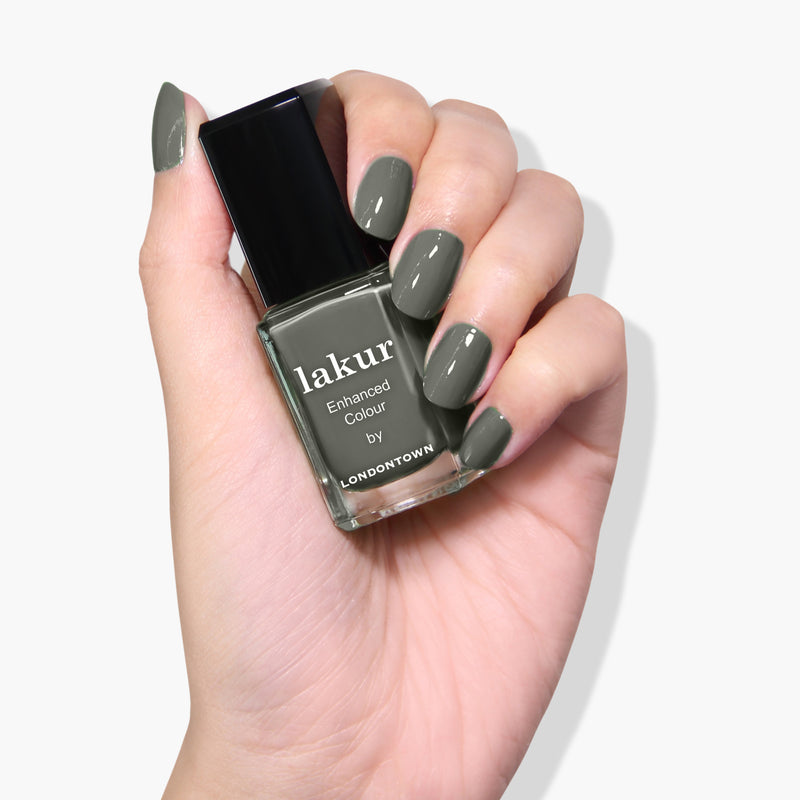 A hand holding a bottle of Star Moss by LONDONTOWN nail polish in an olive shade with matching nails painted to perfection. This vegan, cruelty-free, 16+ Free formula ensures your manicure is not only stunning but also kind to you and the environment.