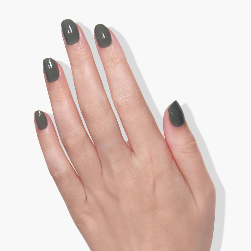 A hand with short fingernails painted in LONDONTOWN's Star Moss, a dark green and glossy gel color, is shown against a white background.