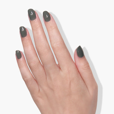 A left hand with short, neatly manicured nails painted in LONDONTOWN's Star Moss (Professional), a dark gray, cruelty-free shade, against a white background.