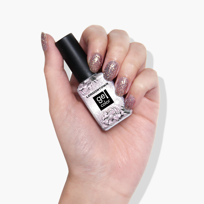 A hand displaying a bottle of LONDONTOWN's Starstruck gel color with glittery, light purple painted nails that shimmer under UV/LED light.