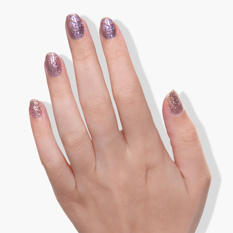 A hand with all five fingers adorned with LONDONTOWN's Starstruck sparkly purple, cruelty-free nail polish is shown against a white background.
