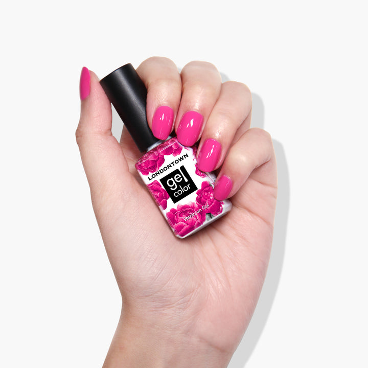 A hand with manicured nails holds a bottle of LONDONTOWN Summer Fling gel color in a shocking pink shade, ready to dazzle under UV/LED light.