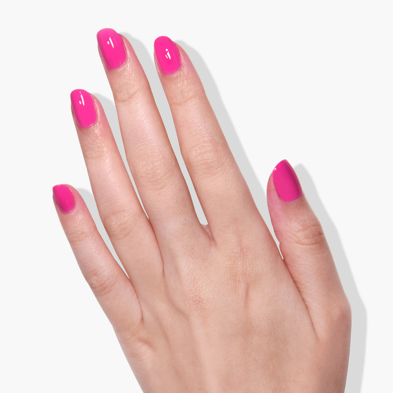 A left hand with natural nails painted in LONDONTOWN's Summer Fling gel color, displaying a striking pink shade, against a white background.