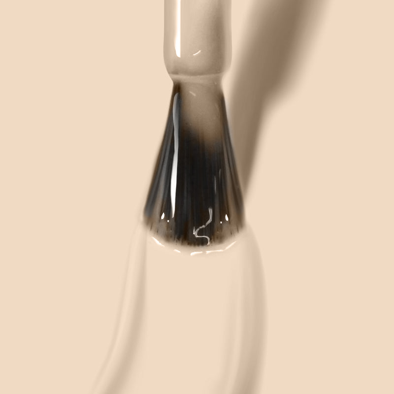 Close-up image of LONDONTOWN's cruelty-free Teatime nail polish brush applying a sheer, barely-there nude shade on a beige background.