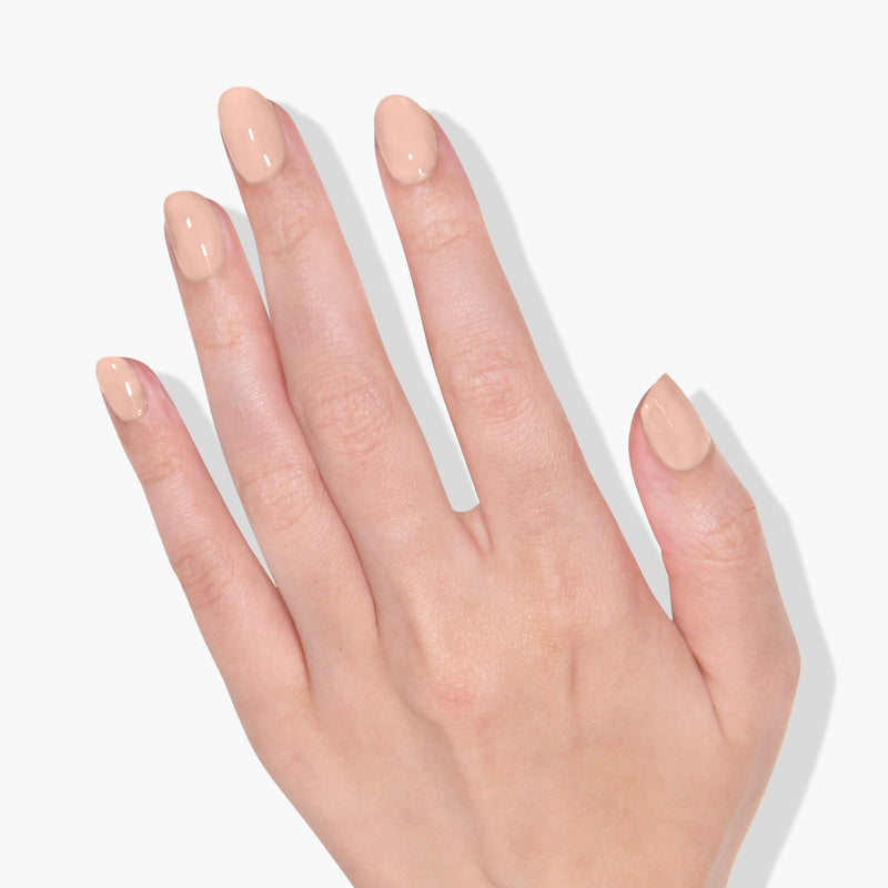 A hand with neatly manicured nails painted in LONDONTOWN's The Full Monty nude UV/LED Gel Color on a white background.