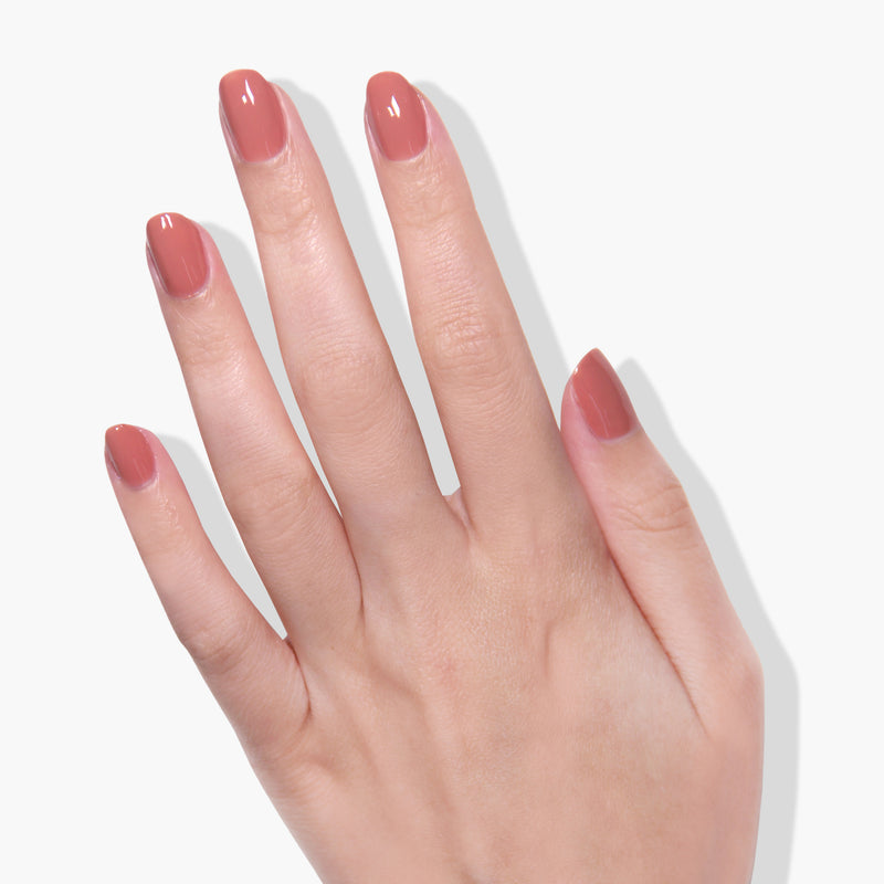 Close-up of a hand with short, neatly manicured nails painted in a glossy, light pink gel color called Toffee Tart by LONDONTOWN, against a plain white background.