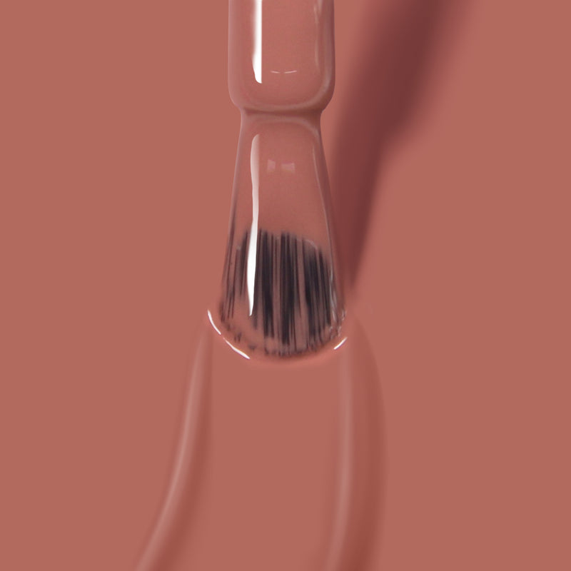 A close-up view of a nail polish brush dipped in LONDONTOWN's Toffee Tart gel polish.