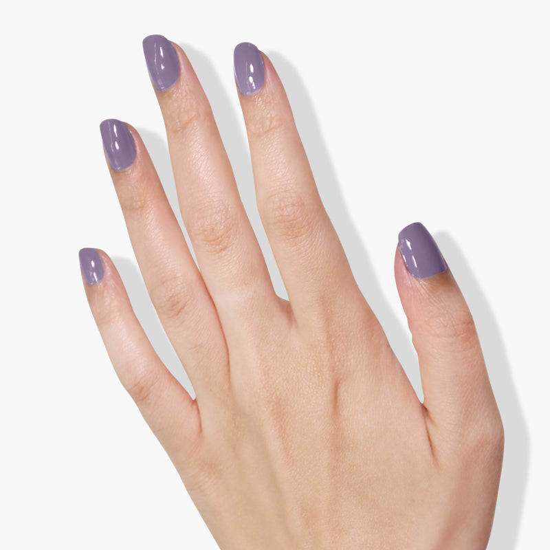 A hand with light skin tone displays nails painted in a glossy lilac crème color against a white background, showcasing LONDONTOWN's vegan cruelty-free nail polish in the shade Trolley Away.