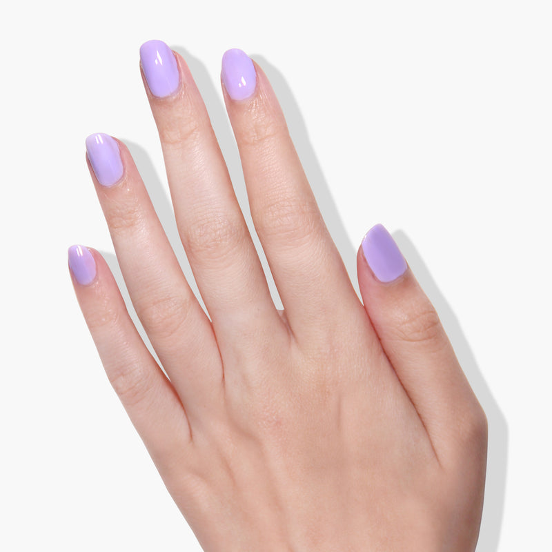 A hand with well-manicured nails painted in Trolley Away, a delicate lilac crème by LONDONTOWN, is shown against a plain white background.