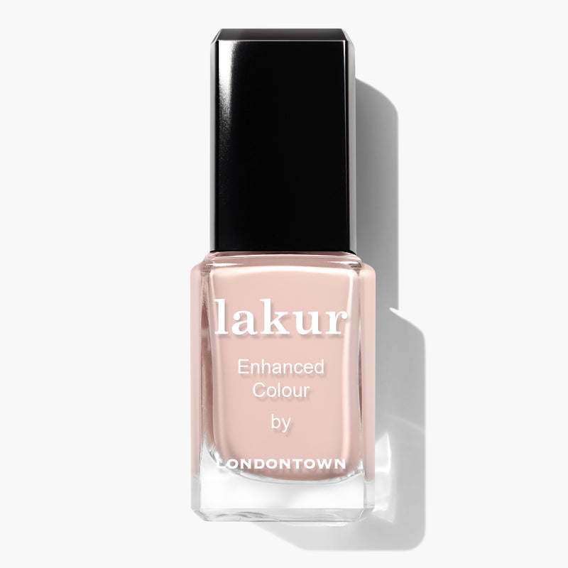 A bottle of LONDONTOWN's Uncovered nail polish, featuring a neutral pink shade reminiscent of a nude polish, with a black cap and text on the front of the bottle.