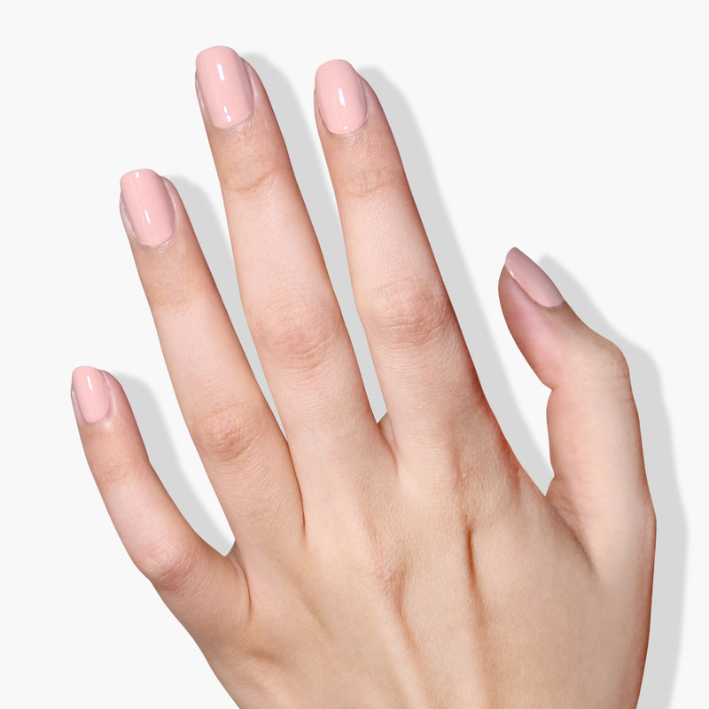 A close-up of a hand with neatly manicured nails painted in LONDONTOWN's Uncovered, a glossy beige cream pink polish—your perfect go-to polish—against a white background.