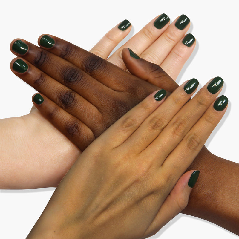 Four hands of varying skin tones, all decorated with LONDONTOWN's Vibe jade green nail polish, are overlapping on a white background.